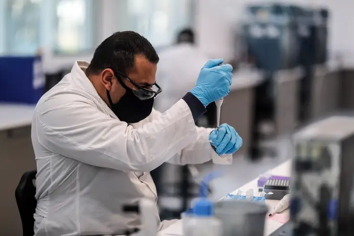 A worker at the mAbxience laboratory, chosen by AstraZeneca for the production in Latin America of the vaccine against COVID-19, transfers a liquid substance from one vial to a microscope slide  in the plant in Buenos Aires, Argentina, in August.